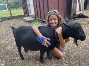 child hugging black goat