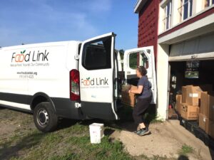 A volunteer unloading a FoodLink van full of boxes of donated food.