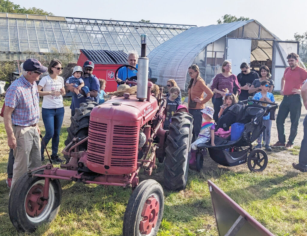 People gathered around an old red tractor