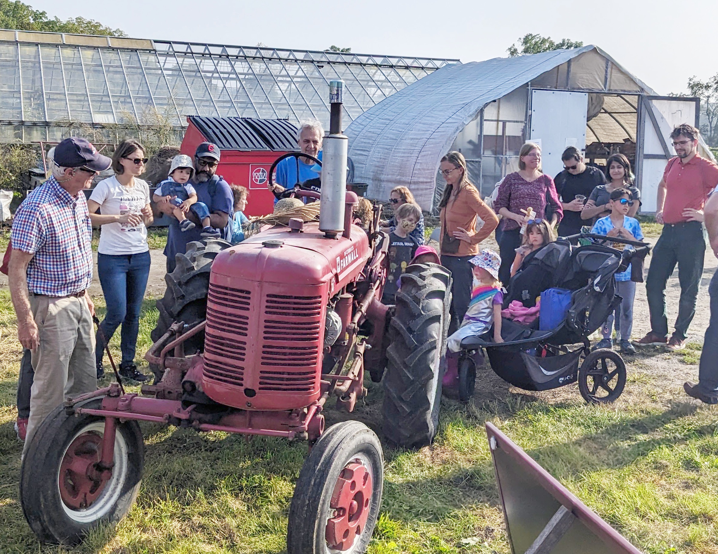 People gathered around an old red tractor