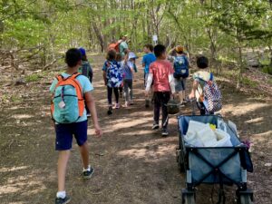 Kids with backpacks walking down a wooded trail